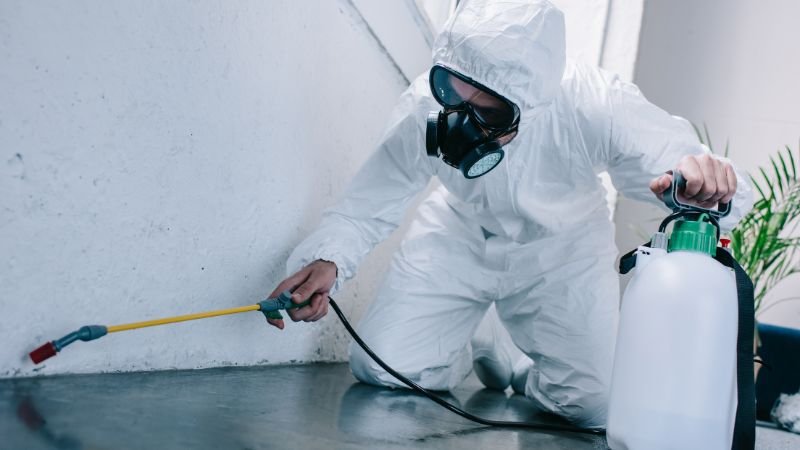 a person in a white suit spraying pesticides